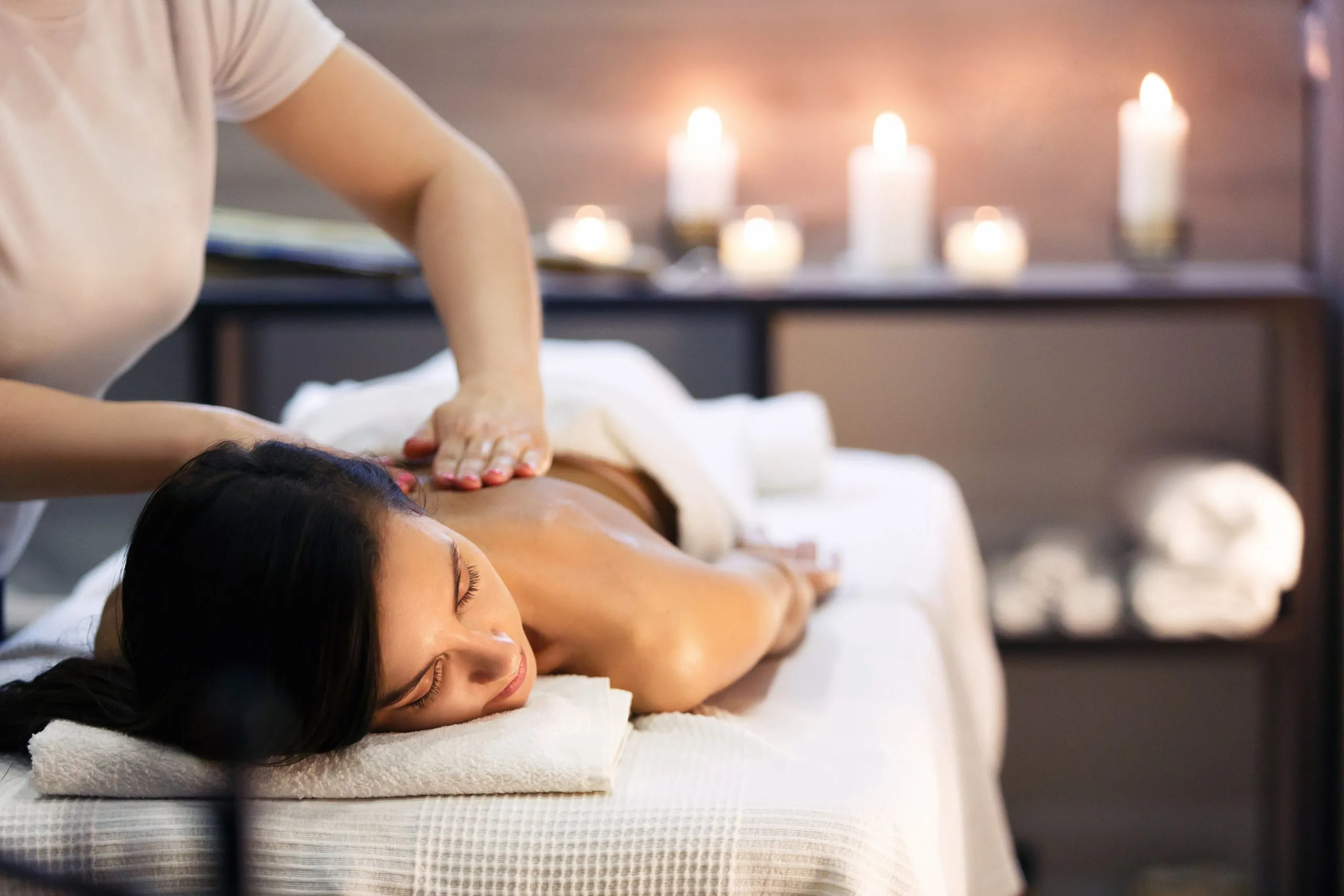 Körpermassage und Spa-Behandlung im modernen Salon mit Kerzenlicht