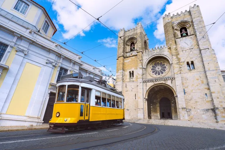 Die Stadt Lissabon und die berühmte gelbe Straßenbahn 28 vor der Kathedrale Santa Maria an einem sonnigen Sommertag. Straßenbahnen in Lissabon, Portugal. Touristenattraktion