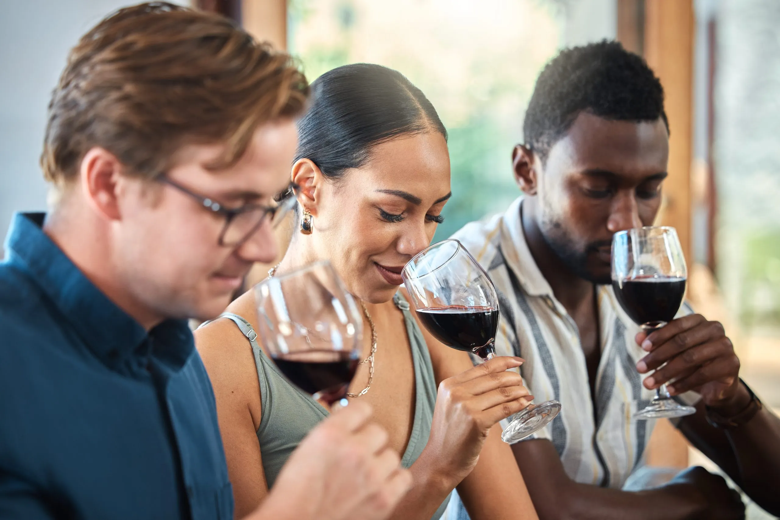 Vielfalt, Luxus und Freunde bei einer Weinprobe in einem Restaurant oder auf einem Weingut, bei der man gemeinsam den Alkohol im Glas riecht. Junge, unbekümmerte Menschen, die zusammenkommen und Spaß haben, bei einer Weintour in einer Destillerie