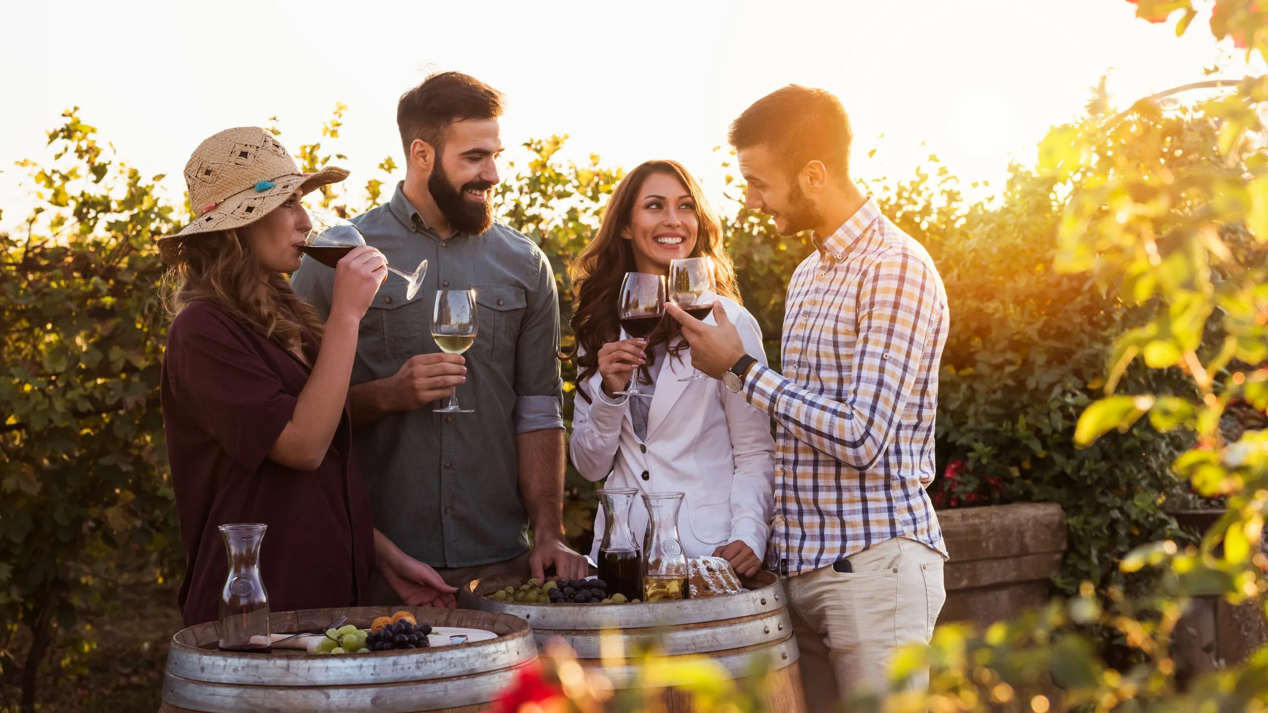 Glückliche Freunde, die sich beim Weintrinken auf einem Weingut amüsieren - Freundschaftskonzept mit jungen Leuten, die die Erntezeit gemeinsam genießen